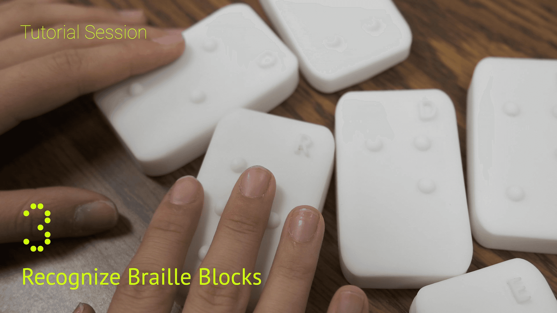 Fingertips reading the raised dots on a letter block